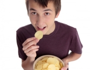 Boy eating chip snack and looking up