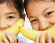 Pre-teen Girls Holding Bananas --- Image by © Julian Winslow/Corbis