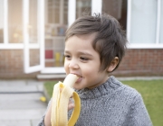 Healthy little boy eating banana with smiling face, Happy kid enjoy eating fresh fruit. Healthy food for children concept.