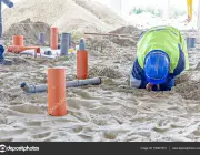 Construction worker is assembly pipeline in sandy soil
