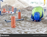 Construction worker is assembly pipeline in sandy soil