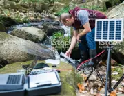 An environmental researcher monitoring water quality from a solar powered field laboratory